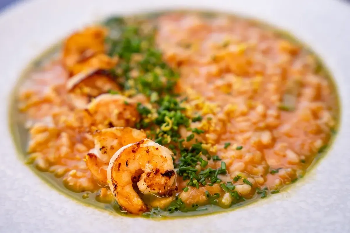 Risoto cremoso de camarão finalizado com ervas