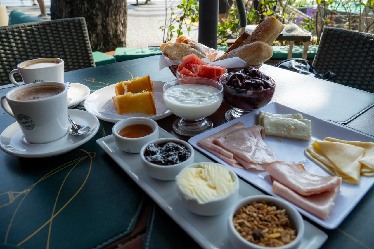 Mesa do Café da Embaixada com pães, frios, açaí, iogurte e café