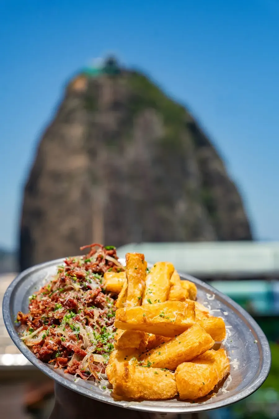 Carne seca acebolada com mandioca frita e o Pão de Açúcar ao fundo