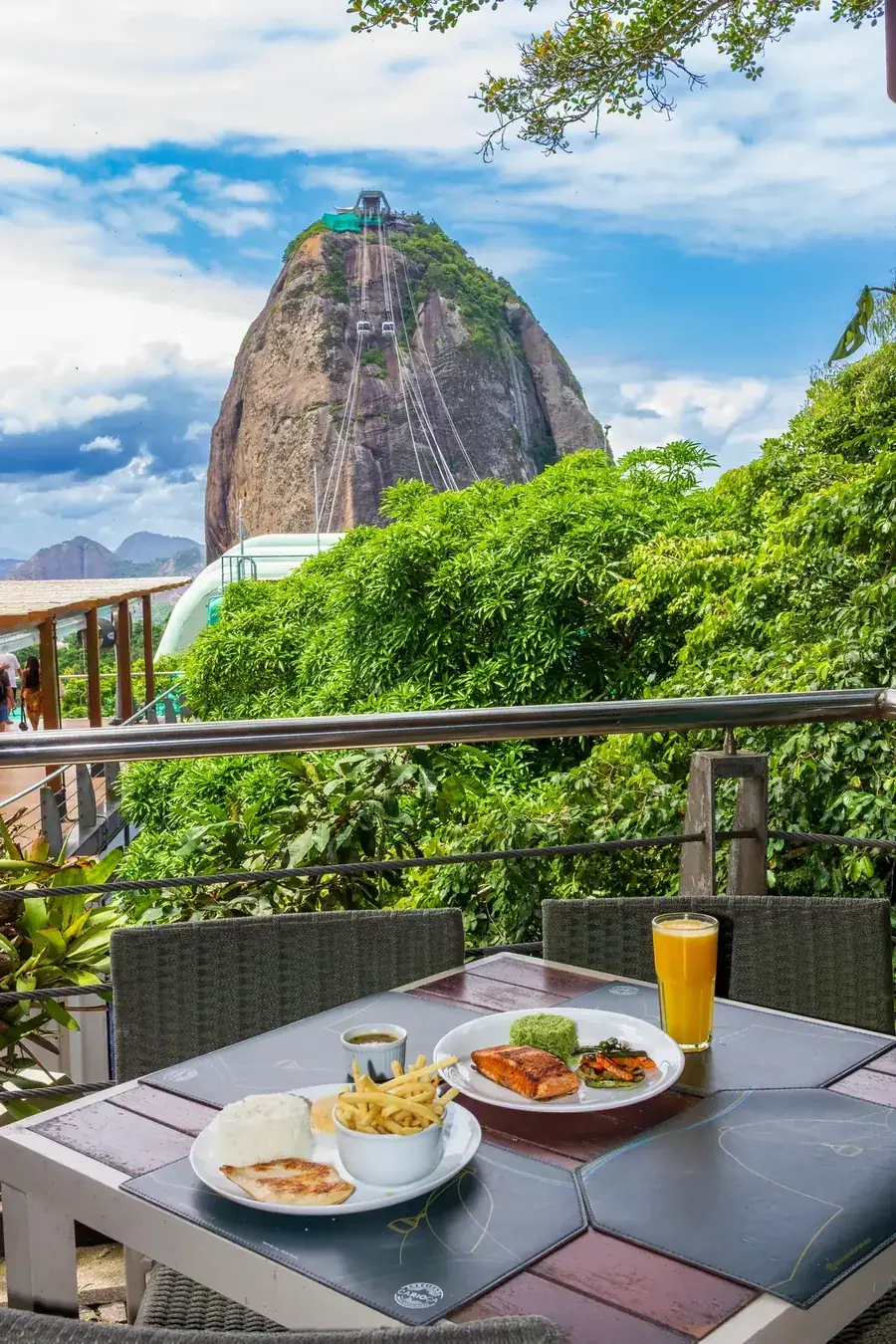 Salmão grelhado com arroz e suco de laranja, com o Pão de Açúcar e o bondinho ao fundo — almoço na Embaixada Carioca, Morro da Urca